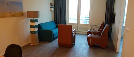 A modern living room with a sofa, two armchairs, a coffee table, and a lamp.