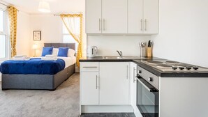 Ein modernes Hotelzimmer mit Bett, einer kleinen Küchenzeile und einem Badezimmer.