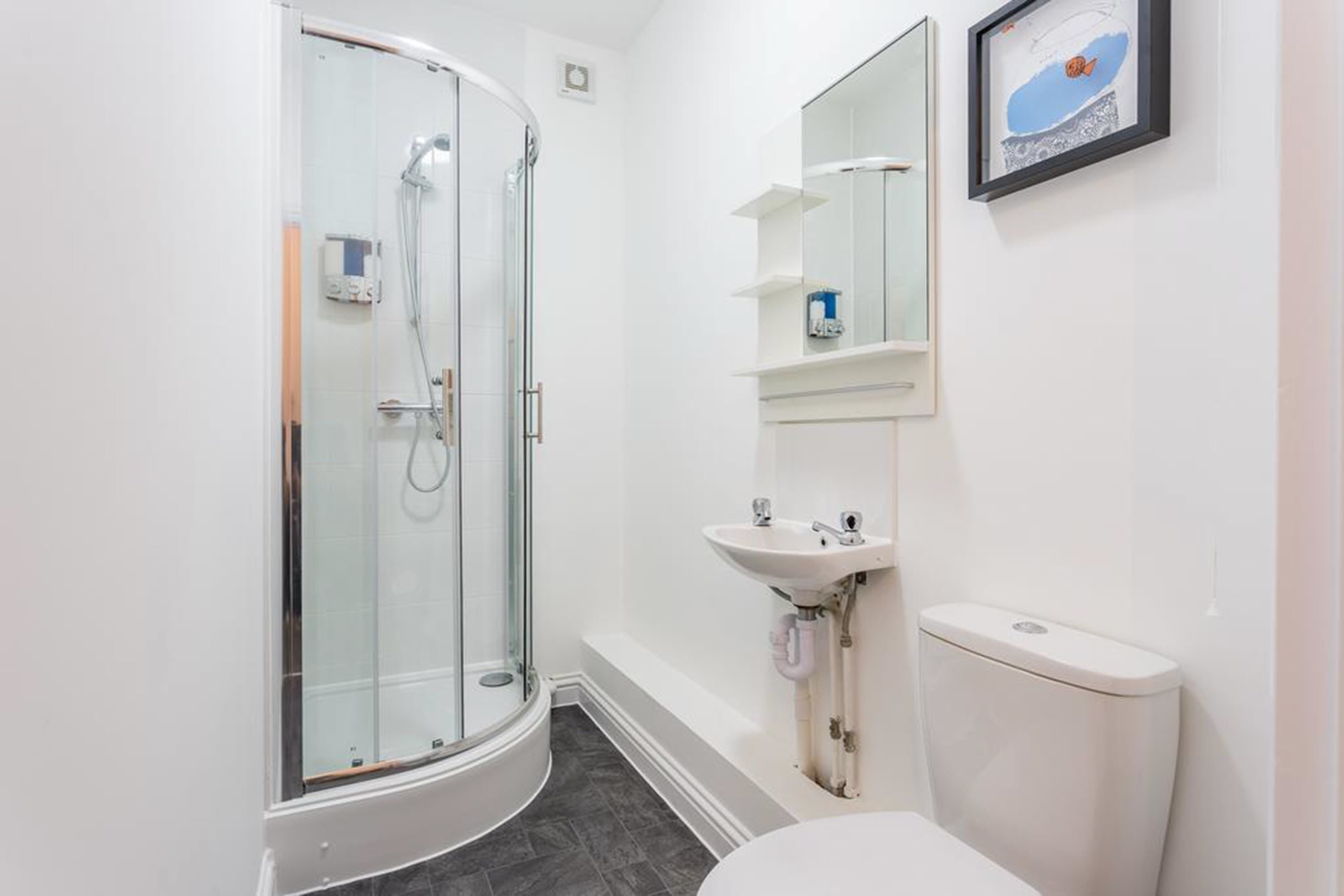 Une salle de bain moderne avec une douche à parois de verre, un lavabo blanc et des toilettes.