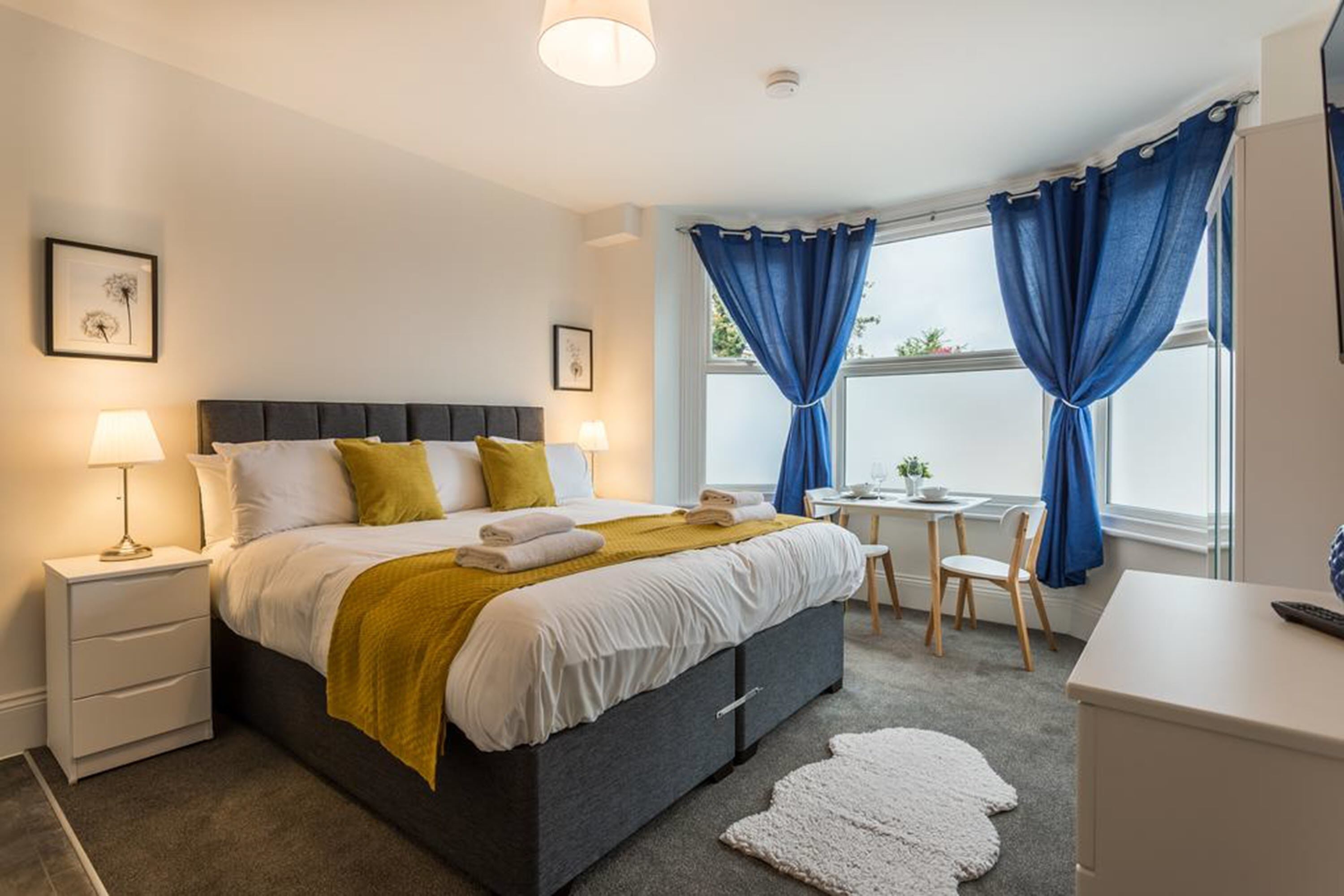 A bedroom with a bed, bedside tables, a desk, and a chair.
