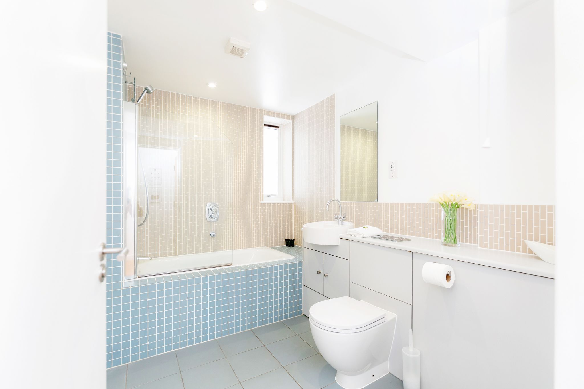 A modern bathroom with a bathtub, toilet, sink, and mirror.