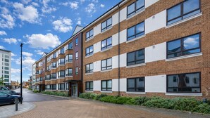A multi-story residential building with a brick facade, large windows, and a paved driveway. - Roomspace Apartments -Kew Bridge Court (London)