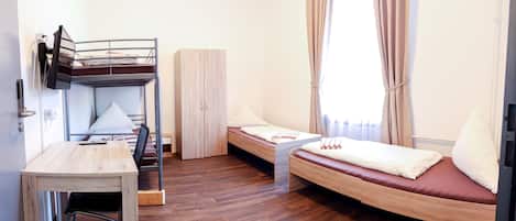 Een kleine kamer met een stapelbed, een bureau en een kledingkast.