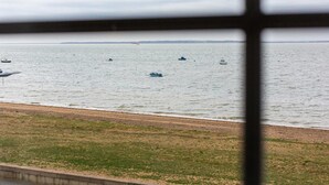A view of a beach with several boats on the water and a sandy shore. - Compass Point by Sorted Stay  (Southend-on-Sea)