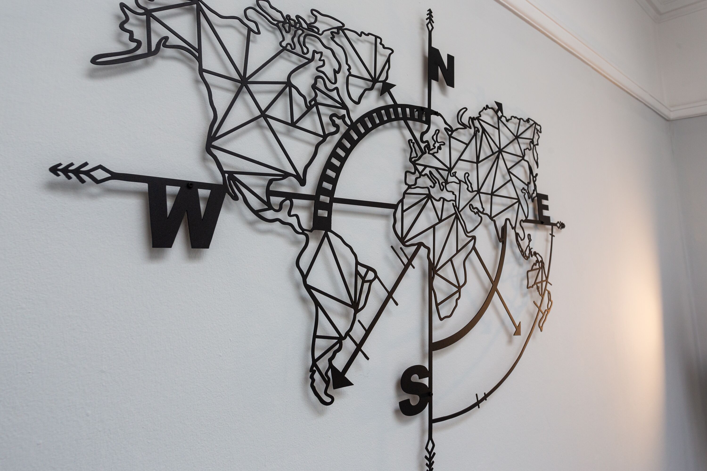Una brújula montada en la pared con un diseño de mapa mundial geométrico.