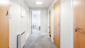 Um corredor com piso revestido de carpete, portas de madeira e uma luminária no teto.