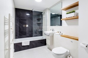 A modern bathroom with a glass-enclosed shower, a white sink, and a toilet.