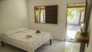 A bedroom with a bed, a TV, and a window with wooden shutters.
