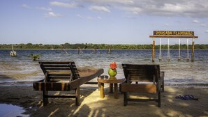 Un banco y una mesa de madera junto a un lago, con un letrero que dice "Pousada Flambiao".