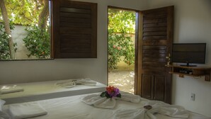 Una habitación con dos camas, televisión y puerta que da al exterior.