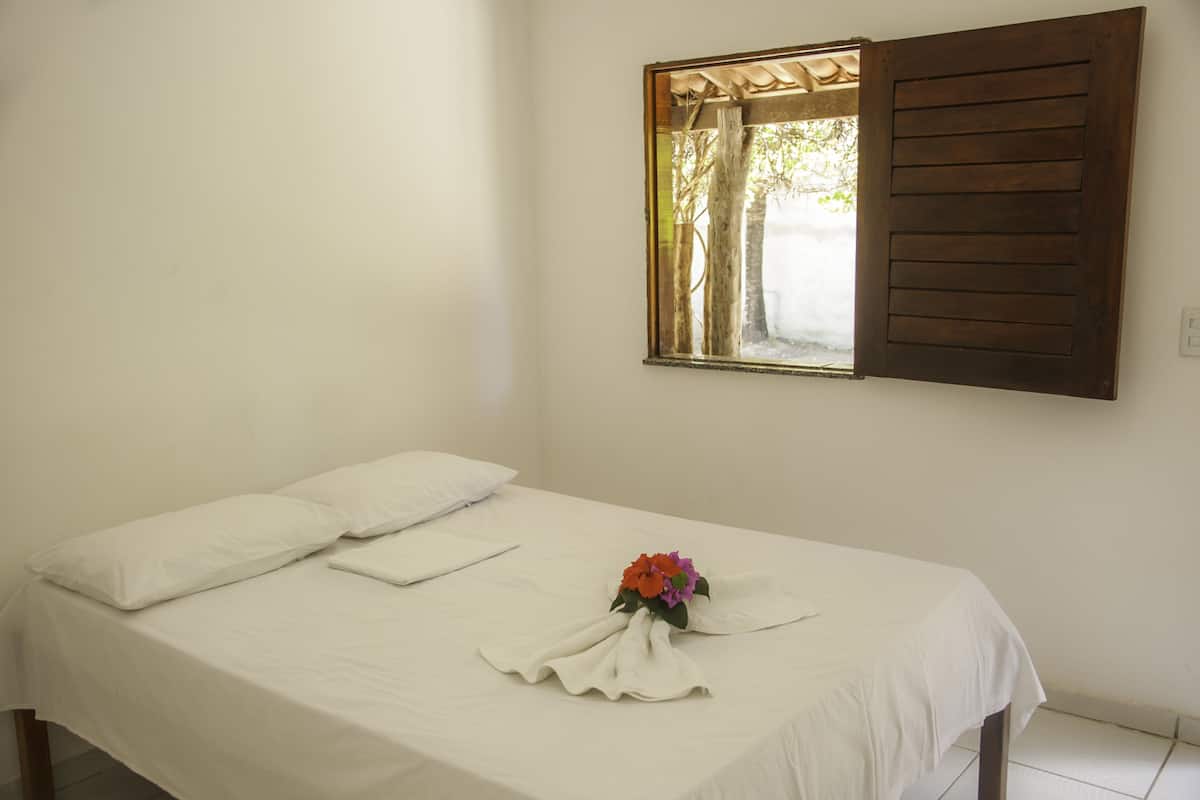 Una cama bien hecha con sábanas blancas y un arreglo floral sobre el edredón.