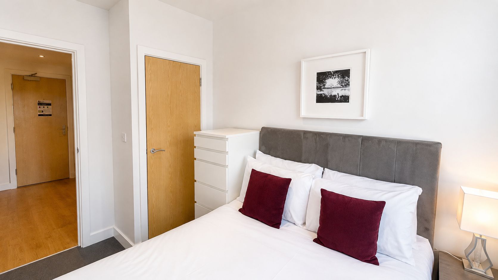 A bedroom with a bed, a nightstand, a dresser, and a framed picture on the wall.