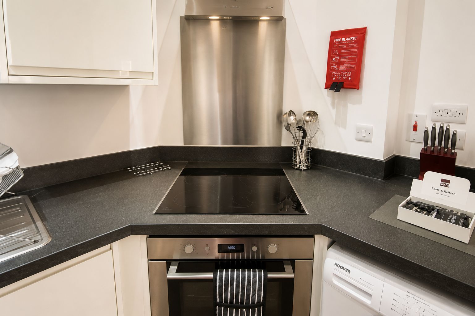 A modern kitchen with a stainless steel range hood, a built-in oven, and a dishwasher.