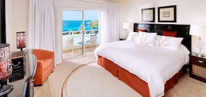 Relax in a spacious room with a large bed, seating area, and ocean views.