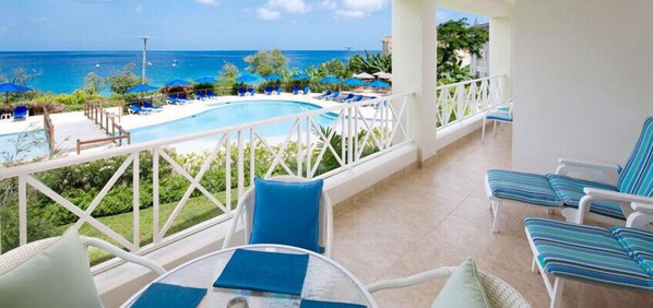 Enjoy the ocean view from this balcony with a pool and lounge chairs below.