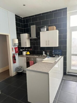 A modern kitchen with black tiled backsplash, white cabinetry, and a central island. - 3 Luxury En-suite Bedrooms (Cardiff)