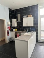 Cozinha moderna com painel de azulejos pretos, armários brancos e uma ilha central.