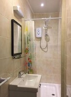 A bathroom with a sink, mirror, shower, and toilet.