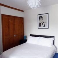 Une chambre à coucher avec un lit, une armoire en bois et un tableau encadré accroché au mur.
