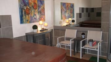 Relax in a spacious room with a large bed, two chairs, and a seating area, surrounded by abstract artwork and a large mirror.