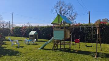 Un parque infantil con tobogán, columpios y una casita.