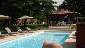 Una piscina al aire libre de temporada, sombrillas