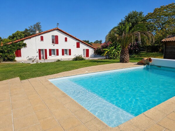 A swimming pool with a white house in the background. - La forge de Clermont - Chambres d'Hôtes (Clermont)