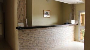 A reception area with a stone wall and a black counter. - Hotel Massoh (Bertoua)