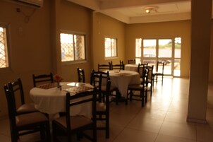 Un comedor con varias mesas y sillas, ventanas amplias y vistas al exterior.