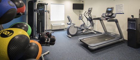 A gym with exercise equipment, including a treadmill, elliptical, and various weights.