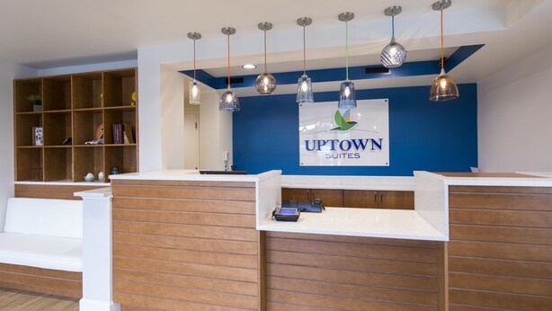 Aula, jossa on sininen seinä, puinen vastaanottotiski ja kyltti, jossa lukee: ”Uptown Suites”.