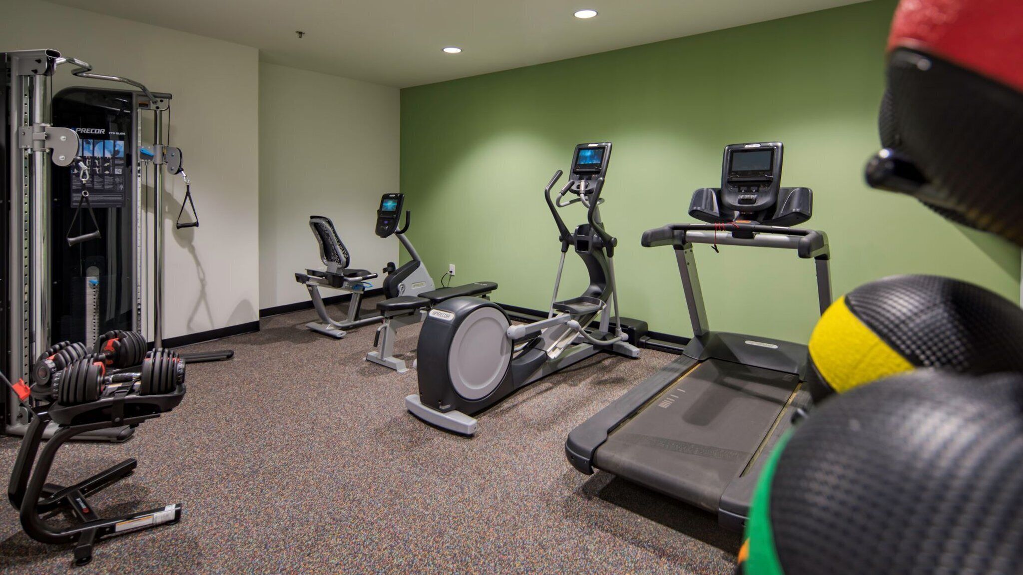Un gimnasio con cintas de correr, elípticas y pesas libres.