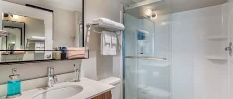 A modern bathroom with a glass-enclosed shower, a double sink vanity, and a large mirror.