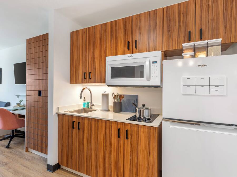 Cocina moderna con armarios de madera, microondas, refrigerador y pileta.