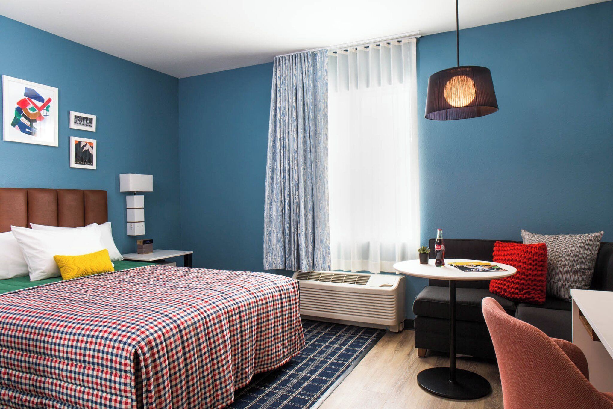Una habitación de hotel con una cama, un sofá, una mesita, una lámpara y una luz en el techo.