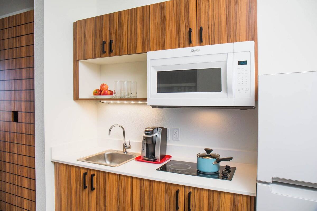 A compact kitchen with a built-in microwave, a coffee maker, a sink, and a stovetop.