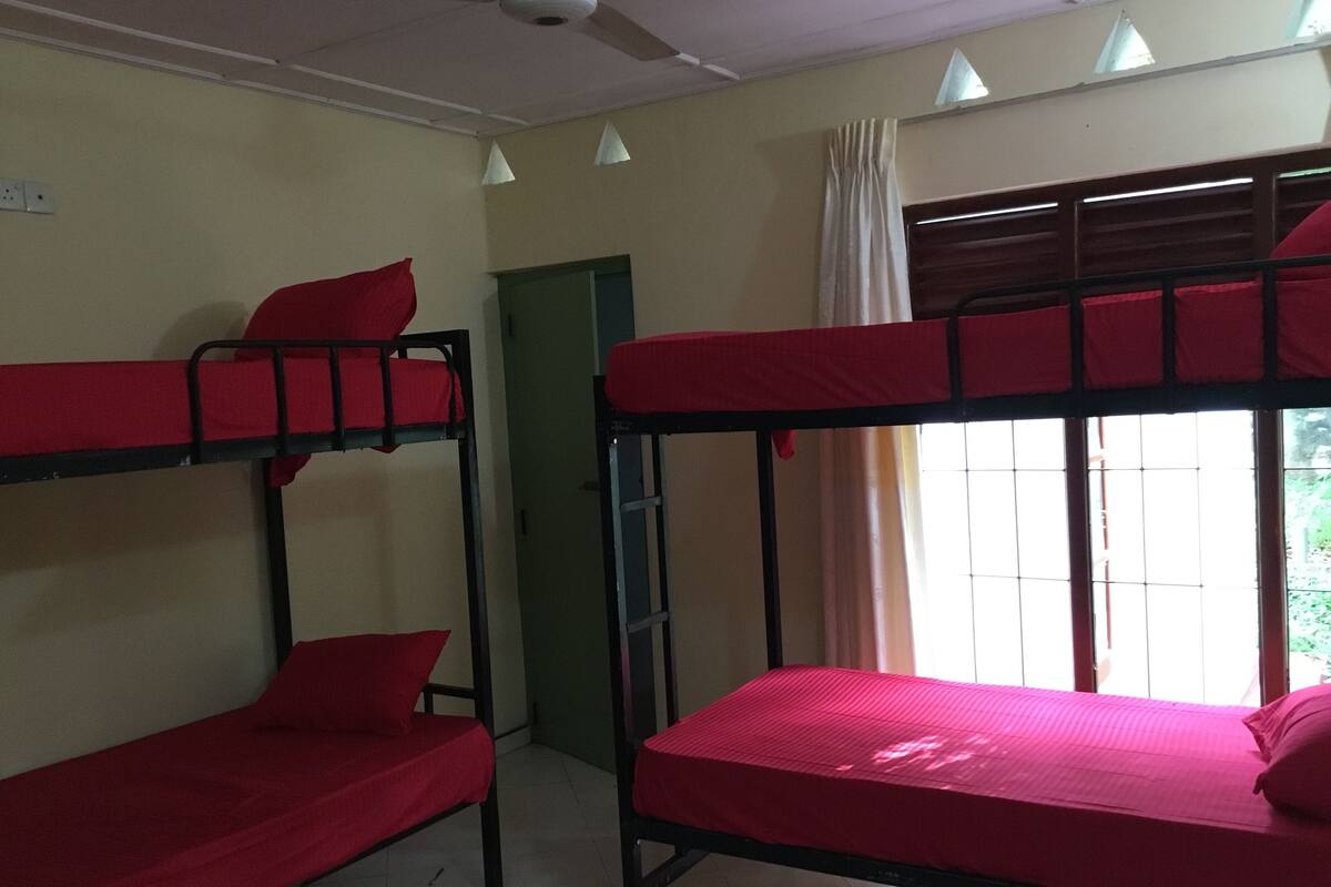 Un dormitorio con literas, ventilador de techo y ventana con cortinas.