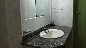 A bathroom with a white sink, dark marble countertop, and white tiled walls. - Benjohostel (Seeduwa - Katunayake)