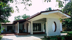 A two-story house with a covered porch, brick exterior, and a circular window. - Benjohostel (Seeduwa - Katunayake)