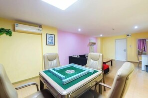Una habitación con mesa de billar, dos sillas, una lámpara y una puerta.