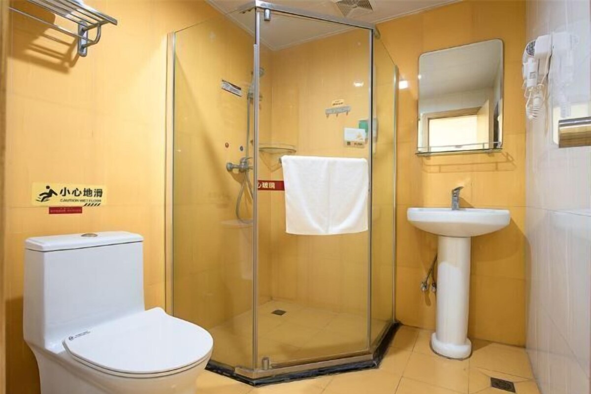 Een badkamer met een douchecabine van glas, een wit toilet en een wastafel met spiegel.