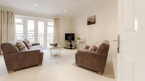 A living room with two sofas, a TV, and a small table with a plant.