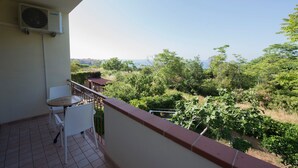 Un balcón con mesa y sillas, con vistas a un paisaje verde y exuberante con árboles y arbustos.