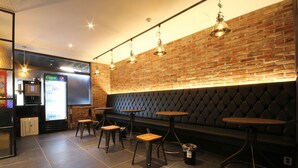 Un espace bar moderne avec des murs en briques, des sièges rembourrés et des luminaires suspendus.