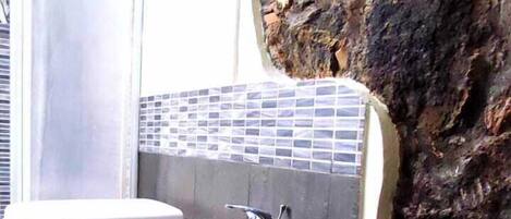 Un baño con una pared de acento de piedra, un lavamanos blanco y un inodoro.