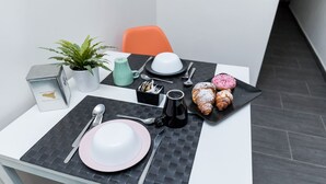 A neatly arranged breakfast table with a white plate, pink bowl, and two pastries on a black placemat. - Passi di Mare Rooms (Giardini Naxos)