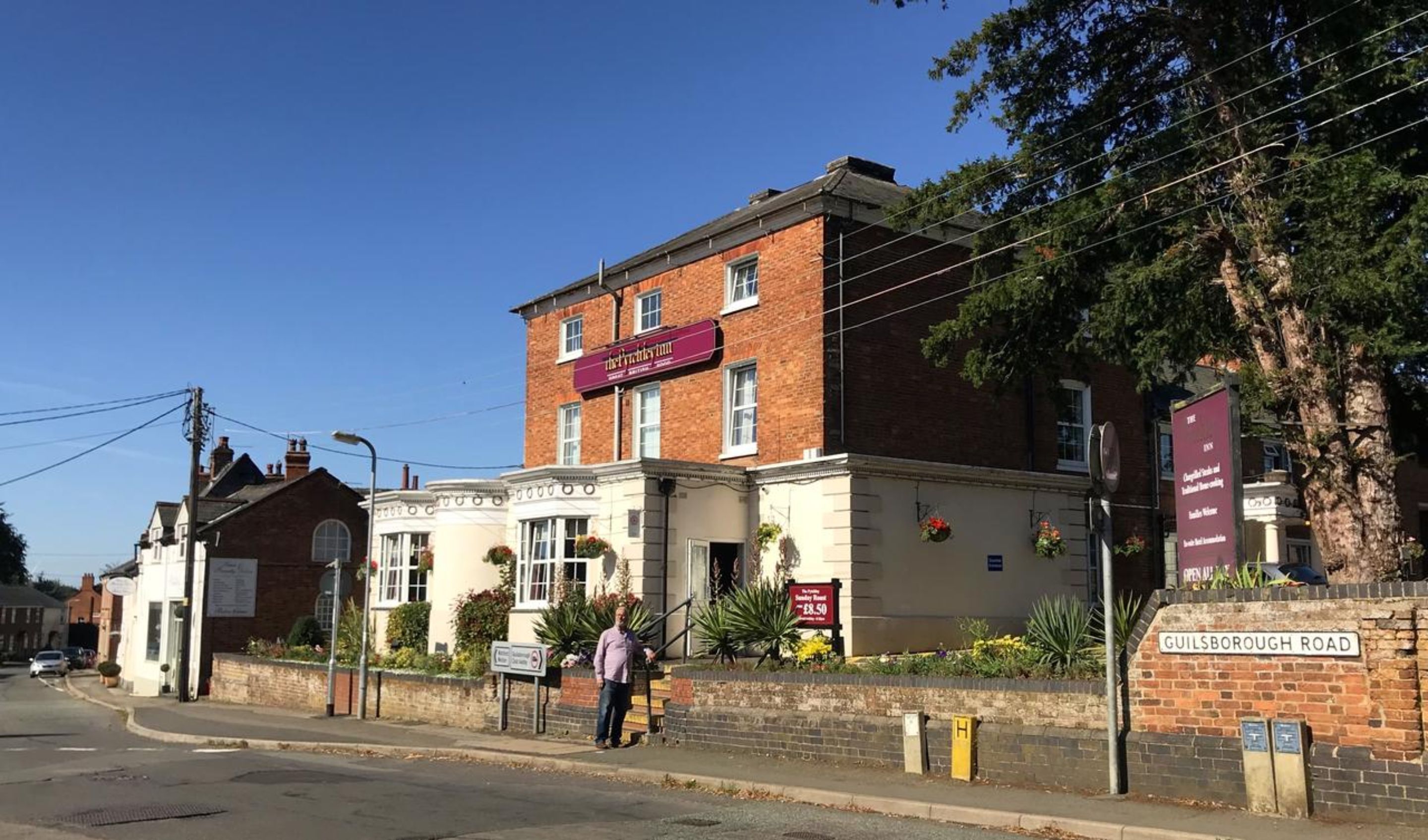 A traditional brick building with a sign for 'The Old Wellington Inn' on the front.