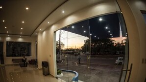 A modern lobby with a large glass window offering a view of the street at dusk.