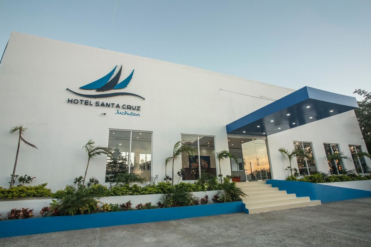 A modern hotel building with a white facade, a blue roof, and a logo featuring a sailboat.