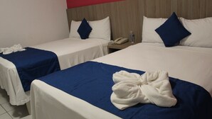 A hotel room with two single beds, each with a blue bedspread and white linens. There is a white bathrobe on the bed in the foreground.